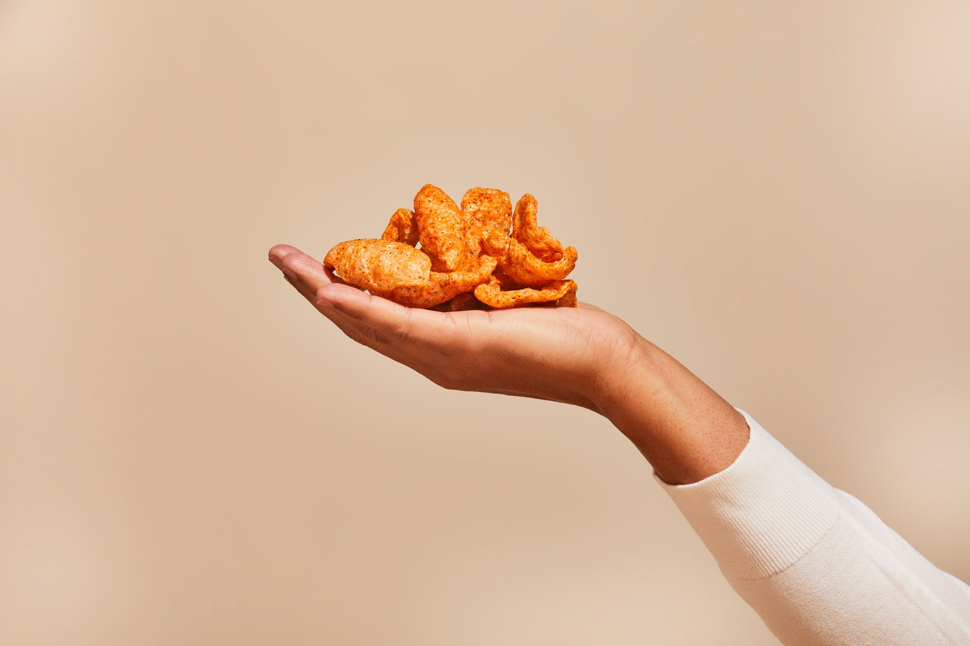 A delicious, crunchy stack of fried chicharrones in the palm of your hand